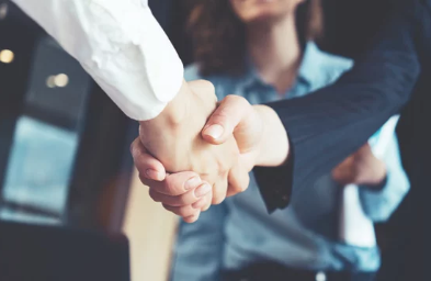 Two people shaking hands as another person observes